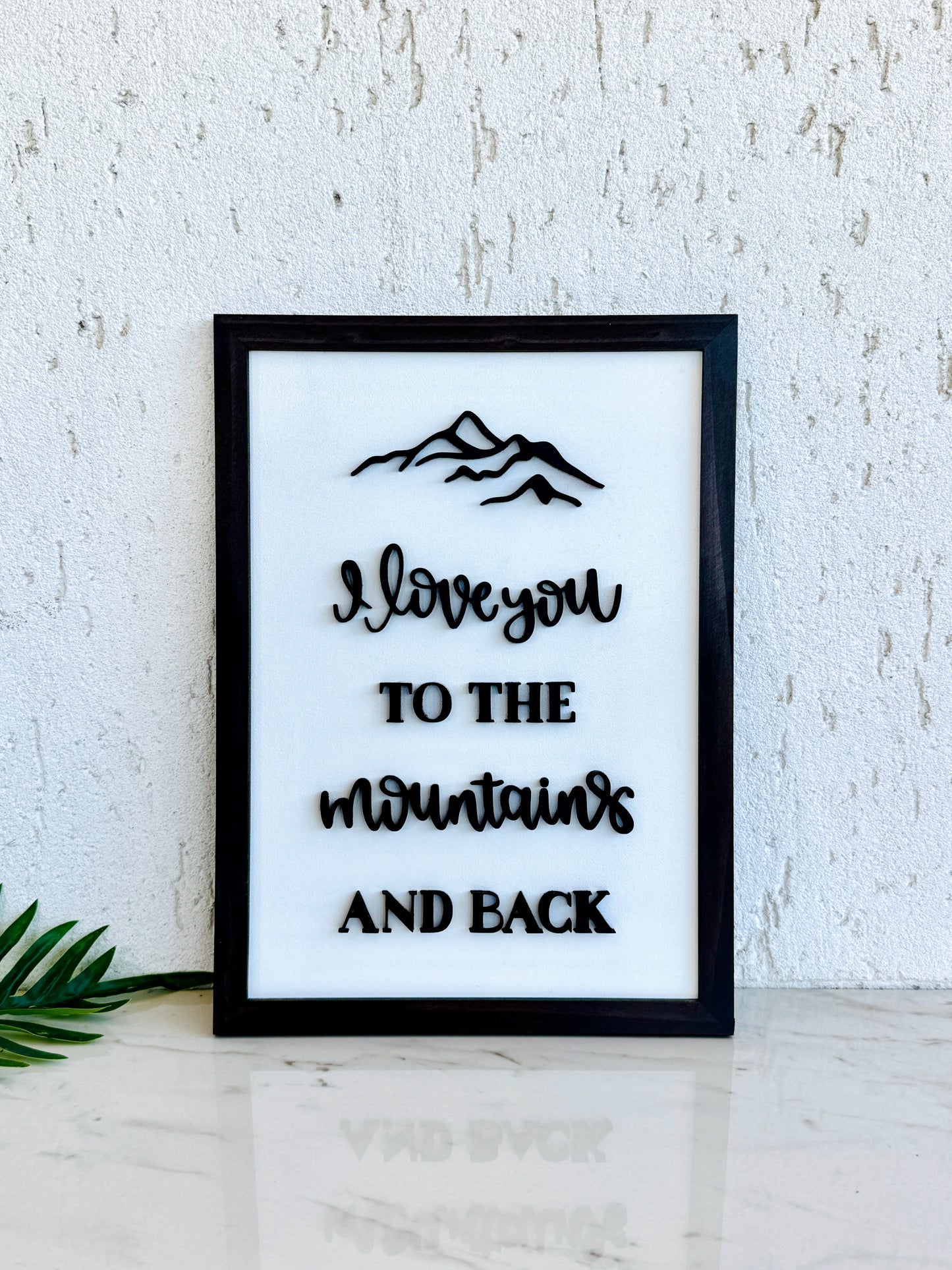 Framed print with 'I love you to the mountains and back' text on a white background