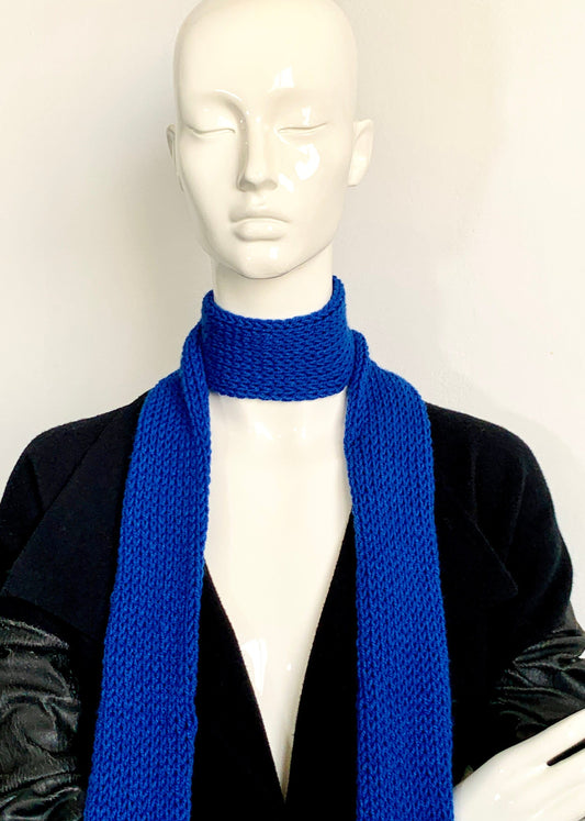A mannequin wearing a cobalt blue skinny knit scarf in a double-layered tube style.