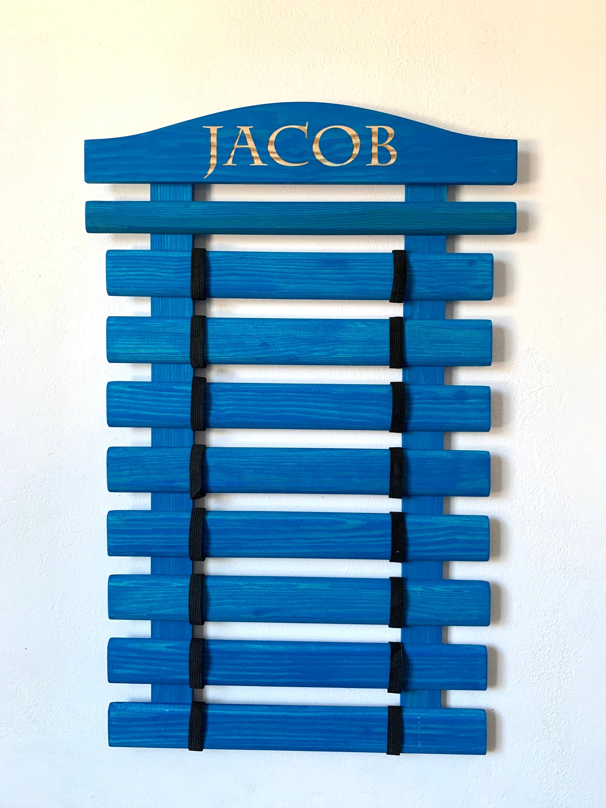 Personalized wooden martial arts belt display rack with engraved name, available in multiple colors and sizes (5-18 belts), perfect for Karate, Taekwondo, and Jiu-Jitsu practitioners.

