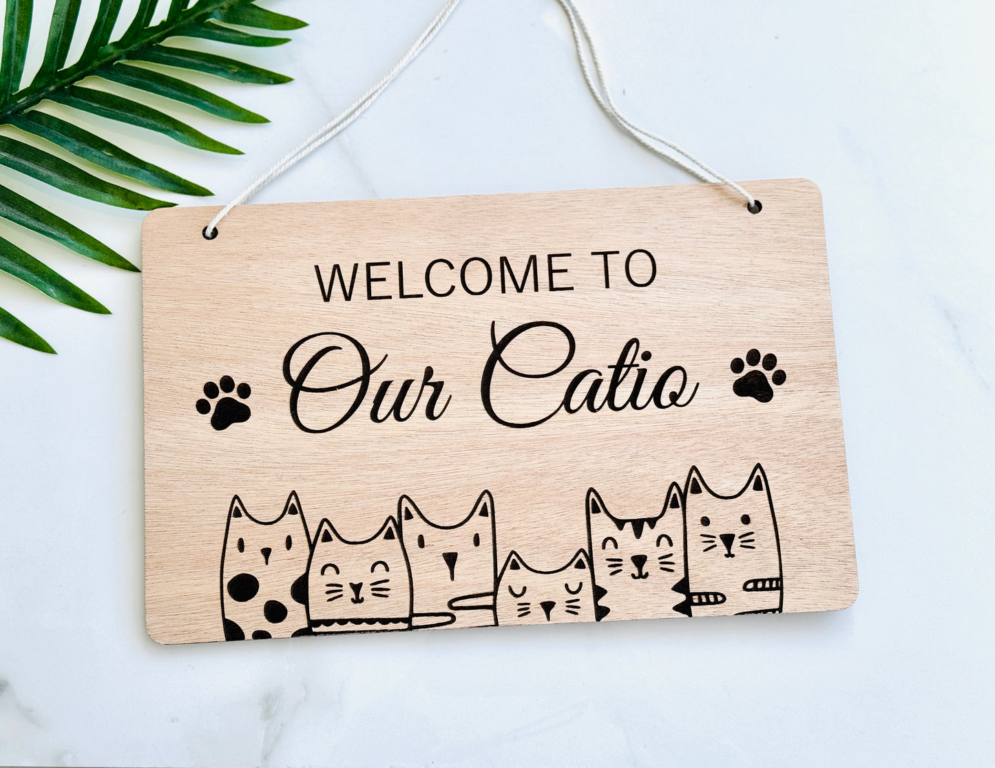 Wooden engraved sign with 'Welcome to Our Catio' text and cat illustrations 