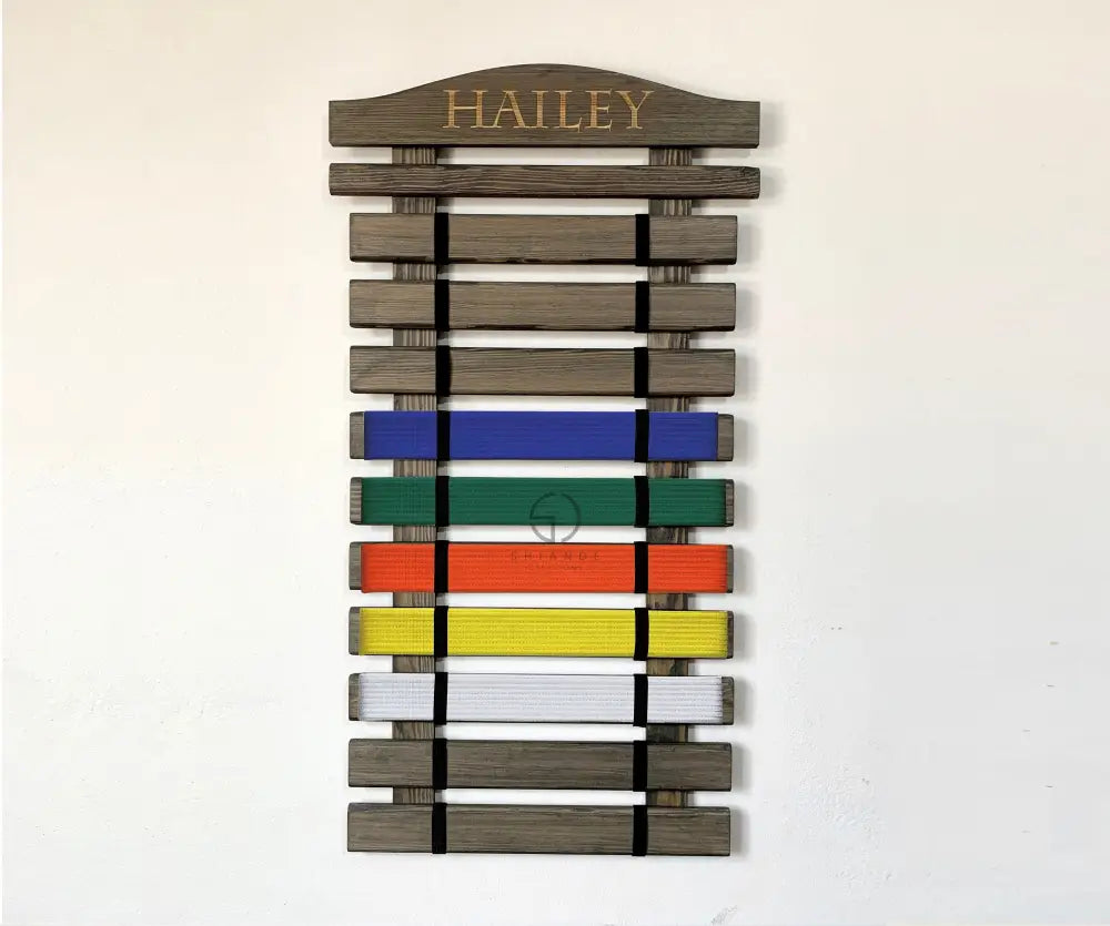 Personalized martial arts belt display rack handmade from solid wood, karate belt holder with engraved name, wall-mounted belt organizer for taekwondo, karate, or jiu-jitsu belts, available in multiple sizes and colors.